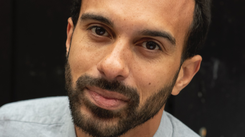 A headshot of the Genesis Future Director 2013 Matthew Xia. Matthew has short dark hair and a short dark beard. He is in front of a plain black background and is wearing a pale grey top.