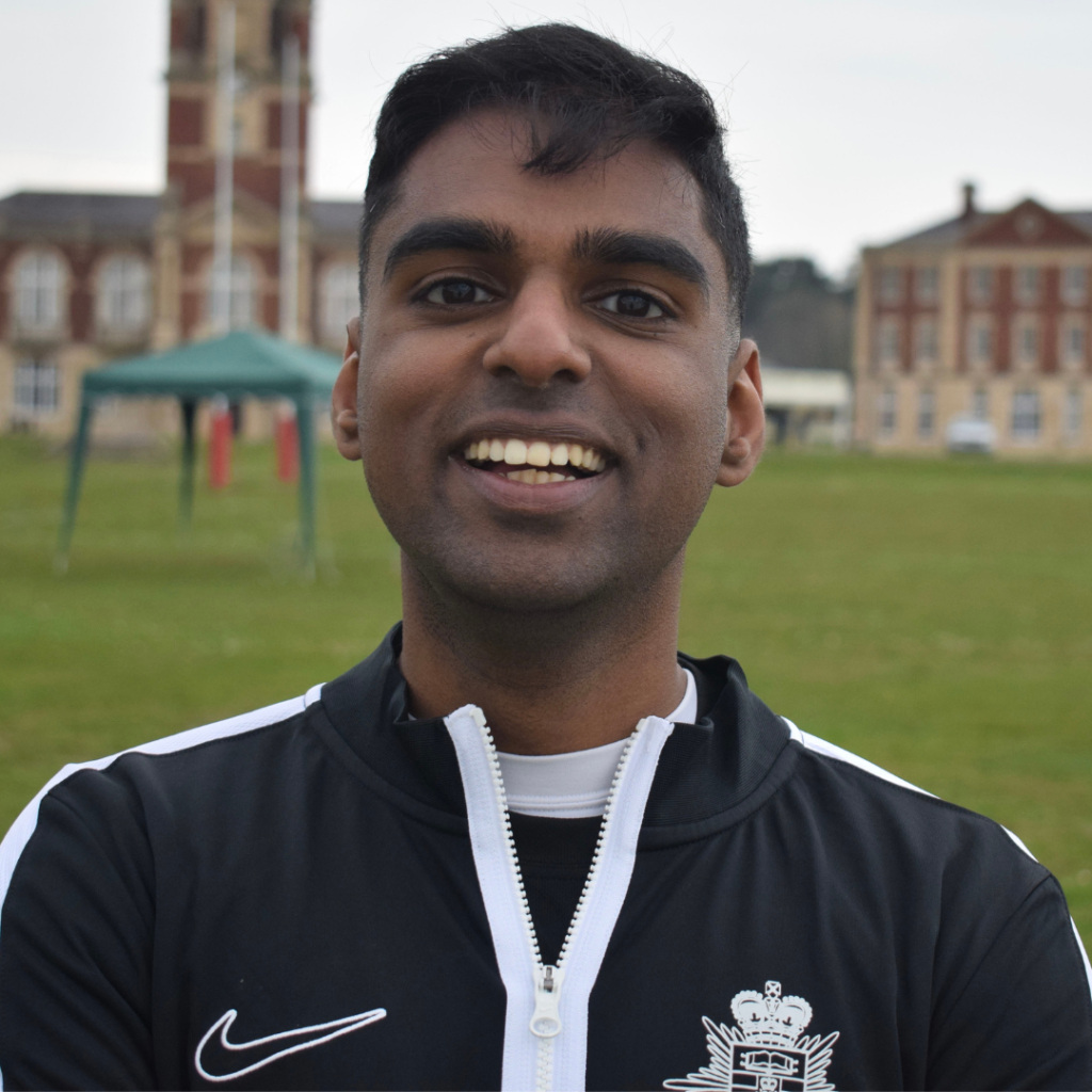 Singer Kevin John stood outside, wearing a sports top, smiling at the camera.