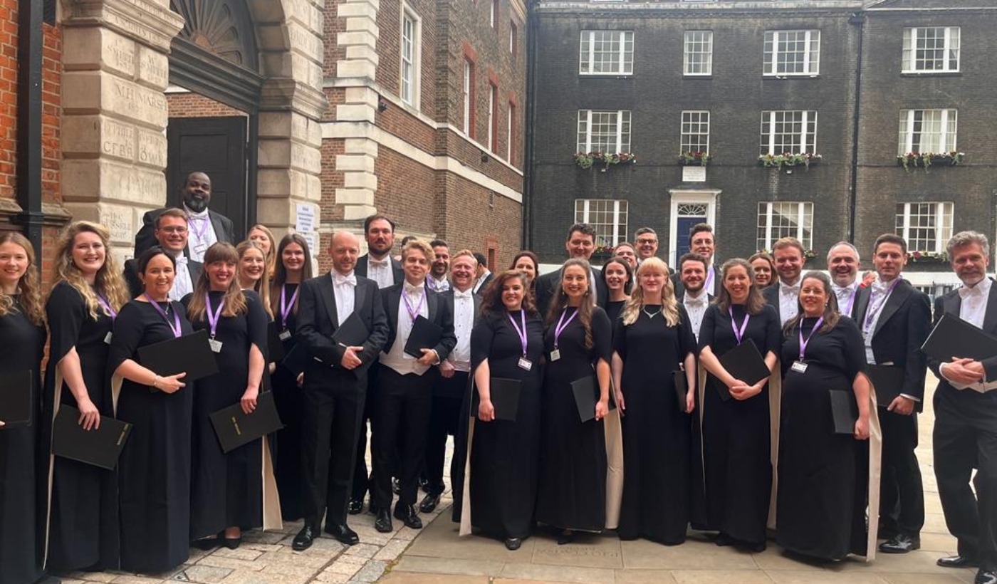 A group photo of members of the Monteverdi Choir stood outside, dressed smartly.